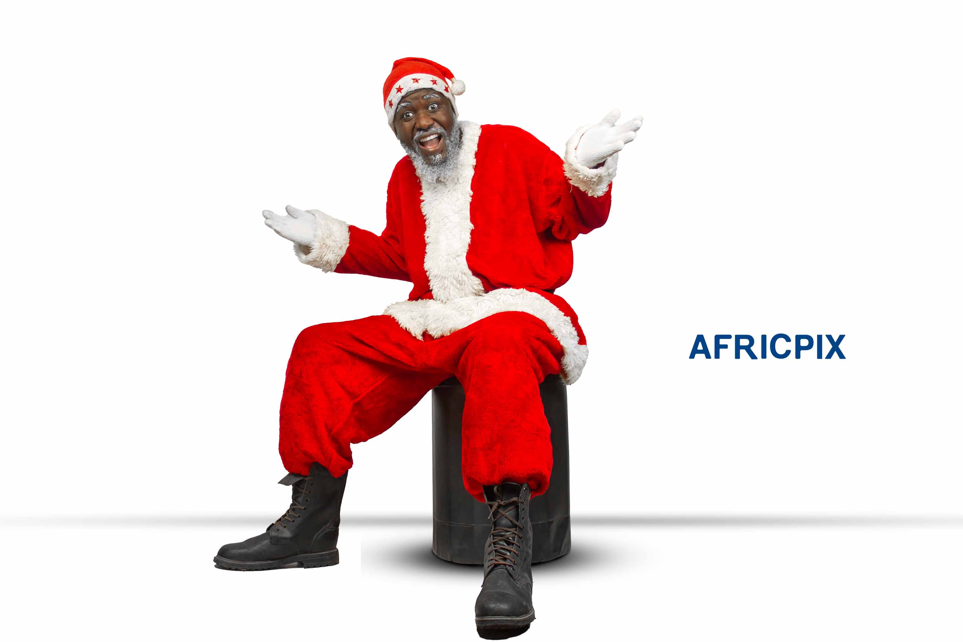 Santa Claus, also known as Father Christmas, sitting on a chair with a joyful expression, raising his hands in excitement.jpg